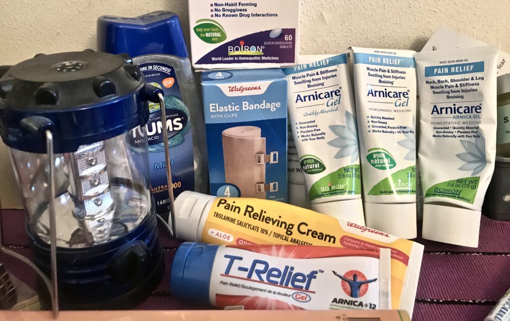 Pain treatments on bedside table. Pain creams, a homeopathic remedy, elastic bandage, Tums. Also a lantern.