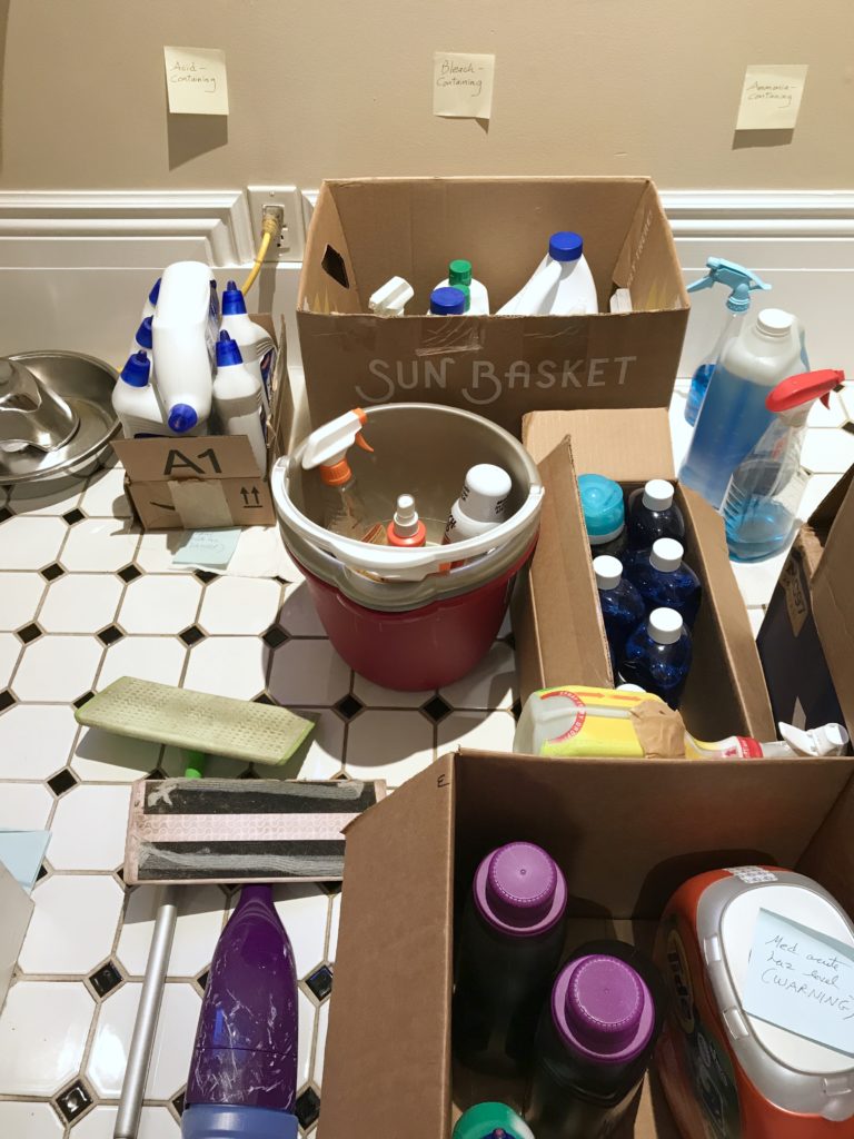 Toxic cleaning-related procucts in cardboard boxes, on glazed ceramic tile floor.